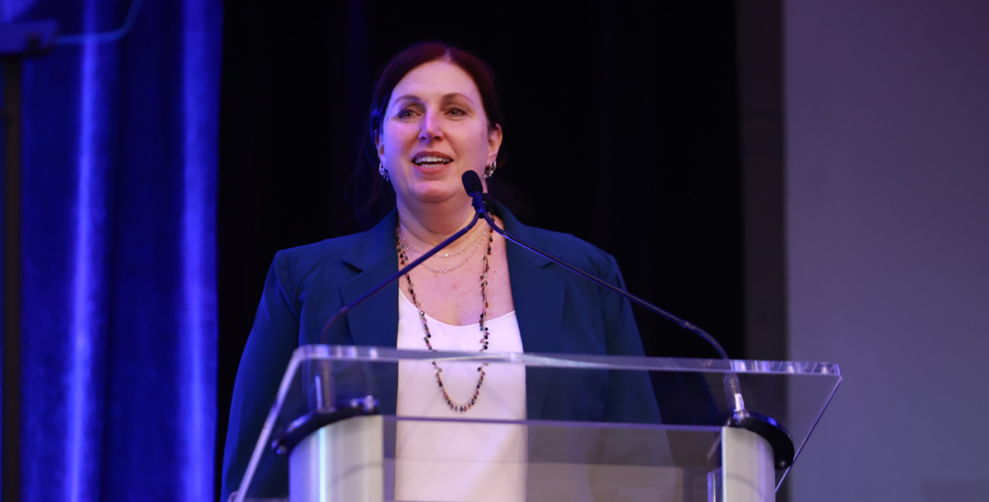 A man standing behind a blue podium with OFC on it speaking.